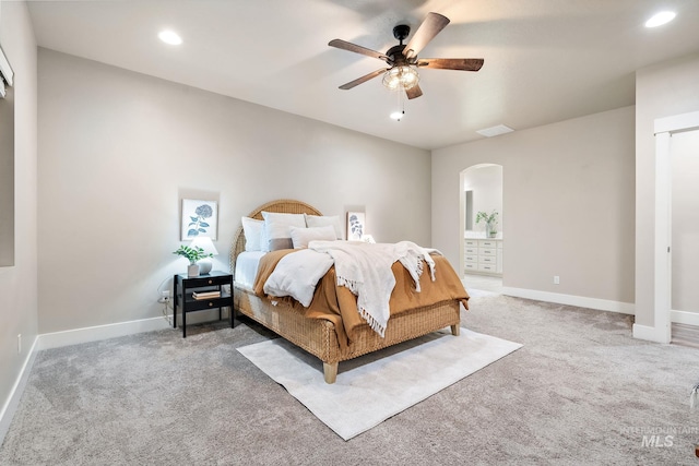 bedroom featuring light colored carpet, arched walkways, and baseboards