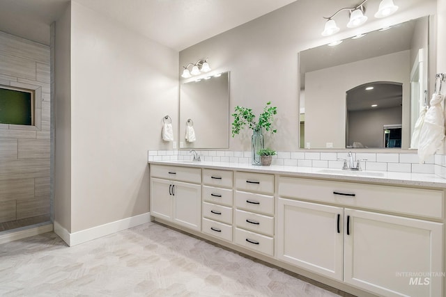 bathroom featuring double vanity, baseboards, backsplash, and a sink