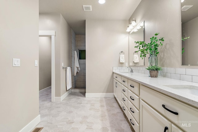 bathroom featuring a sink, visible vents, tasteful backsplash, and double vanity