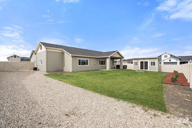 rear view of house with a yard, a fenced backyard, driveway, and a gate