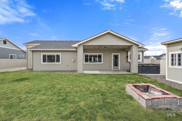 back of property with a patio, fence, a shingled roof, a hot tub, and a lawn