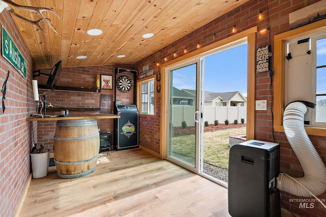 interior space featuring brick wall, wooden ceiling, light wood finished floors, washer / dryer, and vaulted ceiling