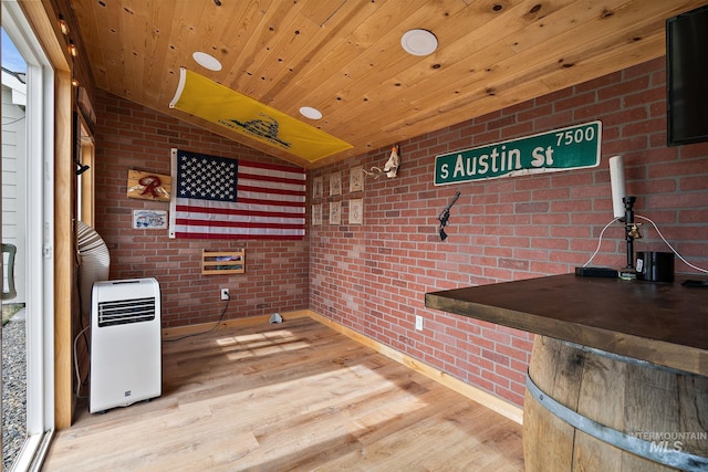 interior space featuring wood finished floors, brick wall, and vaulted ceiling