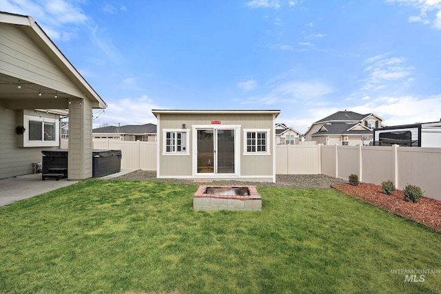 rear view of house featuring an outbuilding, a yard, a fenced backyard, and a hot tub