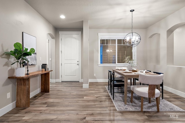 dining area featuring baseboards, recessed lighting, wood finished floors, arched walkways, and a notable chandelier