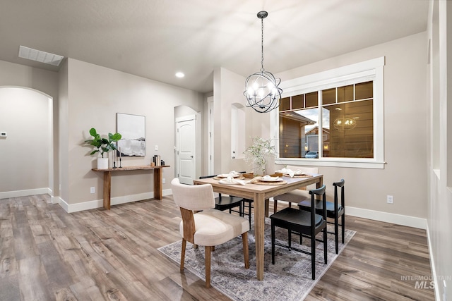 dining room featuring baseboards, arched walkways, visible vents, and wood finished floors