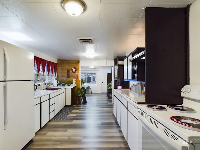 kitchen with dark hardwood / wood-style flooring, white appliances, white cabinetry, and sink