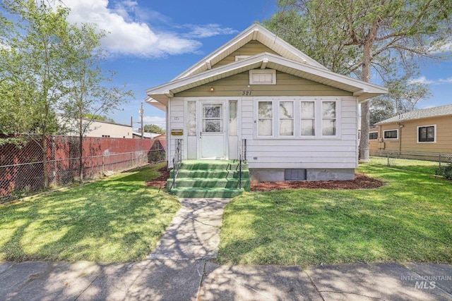 view of front facade with entry steps, a fenced backyard, and a front lawn