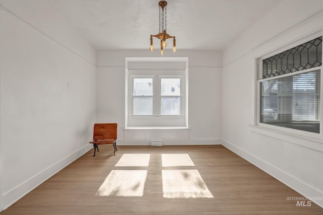 interior space featuring an inviting chandelier, baseboards, and wood finished floors