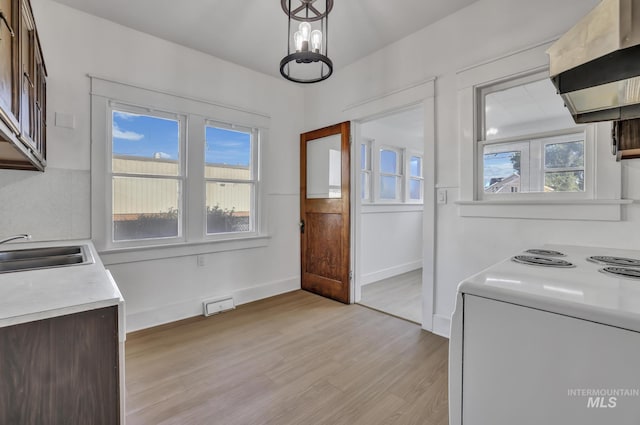 kitchen with baseboards, light wood-style flooring, custom range hood, light countertops, and a sink