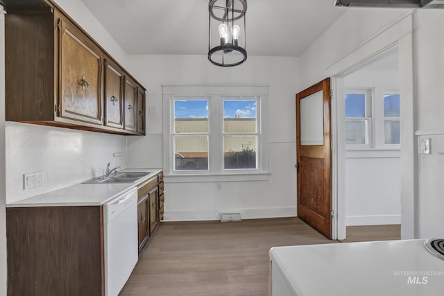 kitchen with dark brown cabinetry, dishwasher, light countertops, light wood-style floors, and a sink