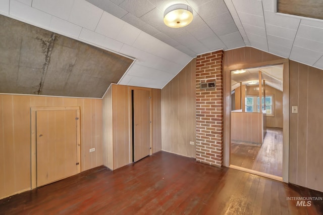 additional living space featuring wood-type flooring, vaulted ceiling, and wood walls