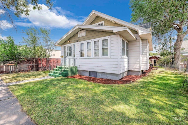 bungalow featuring a gate, fence, and a front lawn