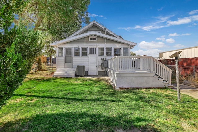 rear view of property with a lawn, cooling unit, fence, and a wooden deck