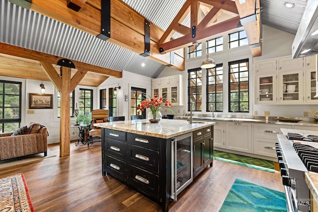 kitchen with a center island, white cabinets, beverage cooler, and high vaulted ceiling