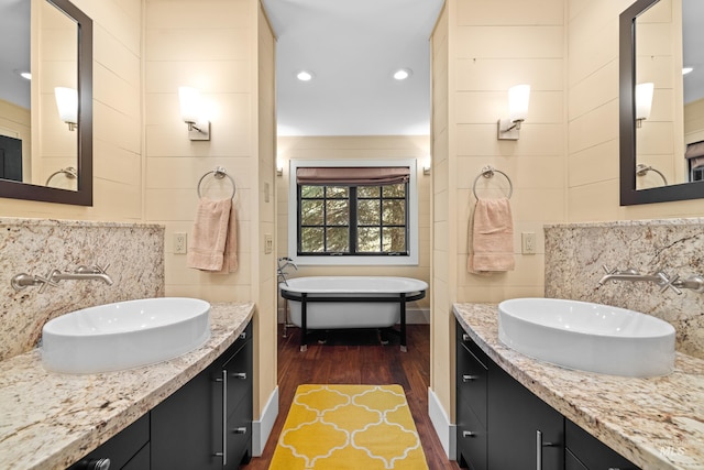 bathroom featuring a bathing tub, tasteful backsplash, wood-type flooring, vanity, and tile walls