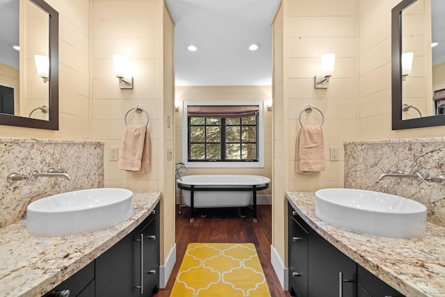 bathroom featuring two vanities, a soaking tub, a sink, and backsplash