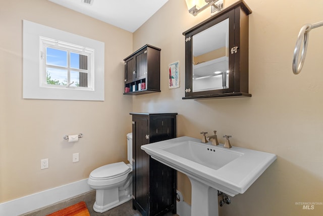 half bath with visible vents, a sink, toilet, and baseboards