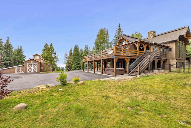 view of yard with an outbuilding, a hot tub, a barn, driveway, and a wooden deck