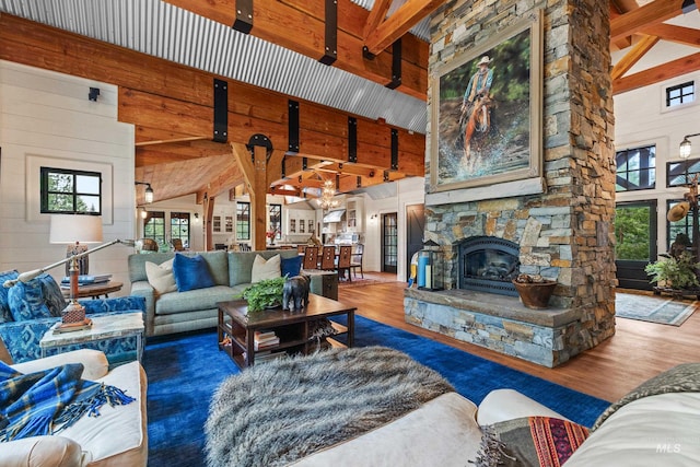 living room with high vaulted ceiling, wood walls, a fireplace, wood finished floors, and beamed ceiling