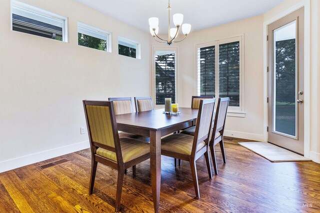 dining room featuring a chandelier, baseboards, and wood finished floors