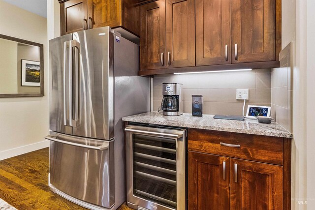 kitchen featuring beverage cooler, freestanding refrigerator, wood finished floors, light stone countertops, and baseboards