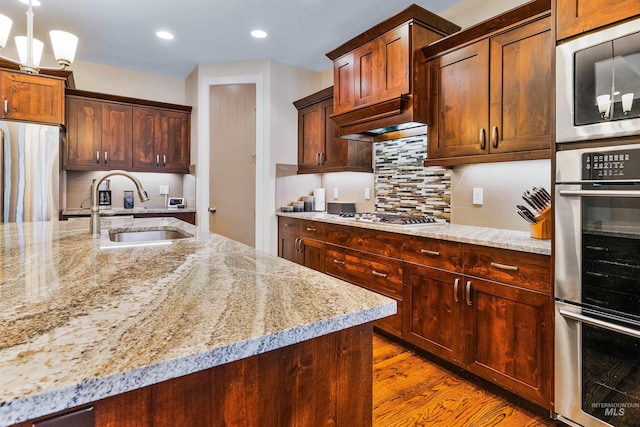 kitchen with stainless steel appliances, light stone counters, a sink, recessed lighting, and tasteful backsplash