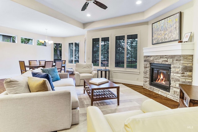 living area with a chandelier, wood finished floors, a ceiling fan, a fireplace, and baseboards