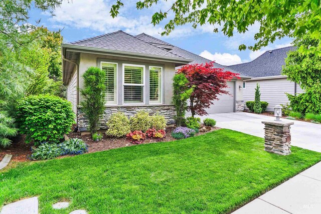 view of front facade featuring stone siding, concrete driveway, a front yard, and stucco siding