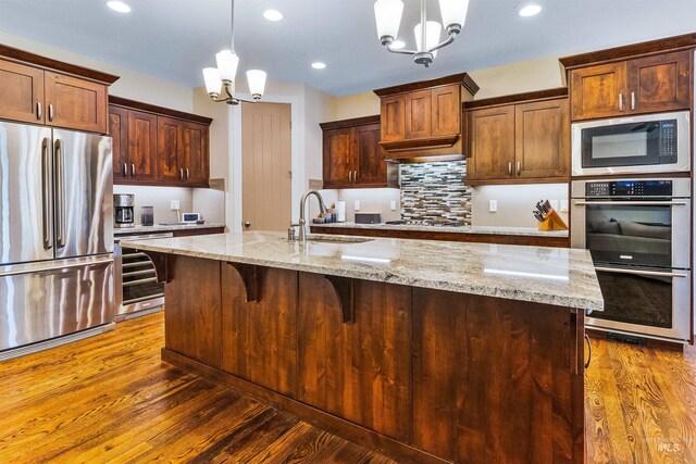 kitchen with stainless steel appliances, a chandelier, a sink, wood finished floors, and recessed lighting