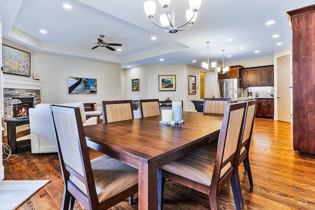 dining space with wood finished floors, a chandelier, a fireplace, and recessed lighting