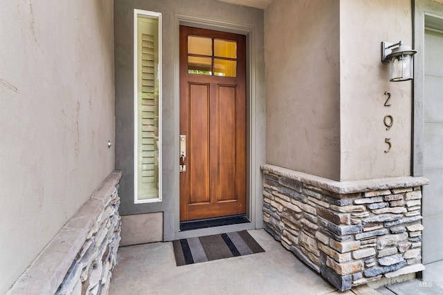 doorway to property with stone siding and stucco siding
