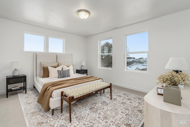 bedroom with multiple windows and light carpet