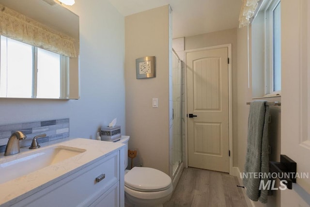 full bathroom with decorative backsplash, vanity, toilet, a stall shower, and wood finished floors
