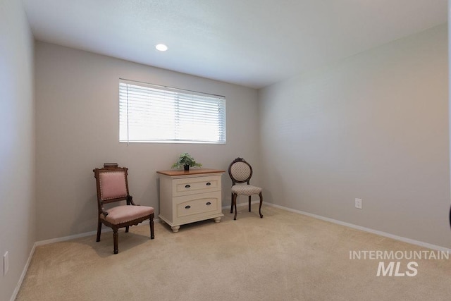 sitting room with baseboards and light carpet
