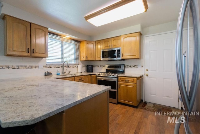 kitchen featuring dark wood-style flooring, appliances with stainless steel finishes, decorative backsplash, and a sink