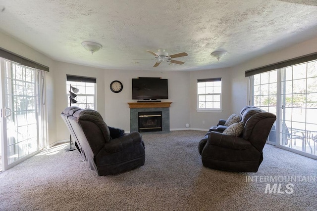 living room featuring ceiling fan, a textured ceiling, and carpet flooring