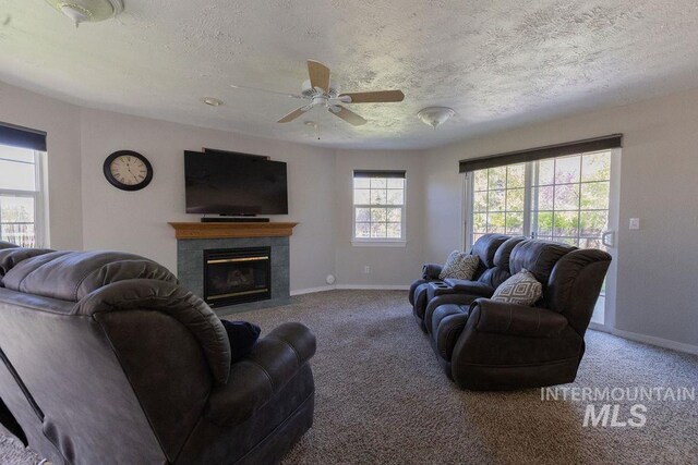 carpeted living room with baseboards, a ceiling fan, a textured ceiling, and a fireplace