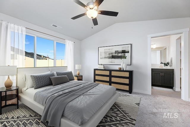 bedroom featuring ensuite bath, ceiling fan, light carpet, and lofted ceiling