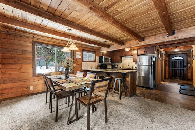 unfurnished dining area featuring dark colored carpet, beam ceiling, wooden ceiling, and wooden walls