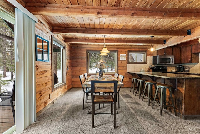 dining room with beamed ceiling, wood walls, wood ceiling, and dark carpet