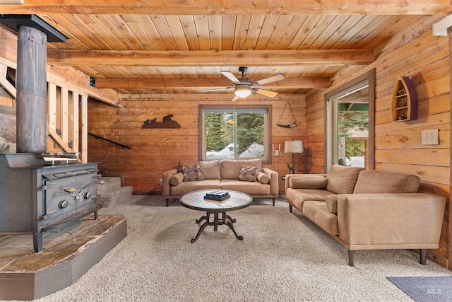 living room with beamed ceiling, wooden ceiling, a wood stove, and wooden walls