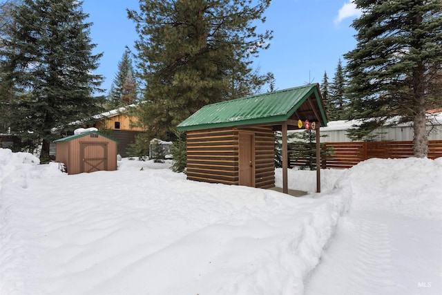 snowy yard featuring a shed