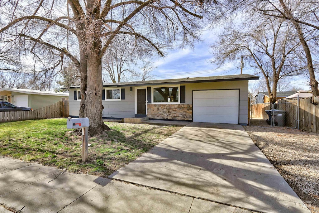 ranch-style house featuring driveway, an attached garage, and fence