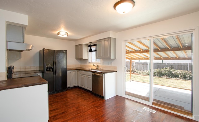 kitchen with dark countertops, visible vents, under cabinet range hood, dishwasher, and black refrigerator with ice dispenser