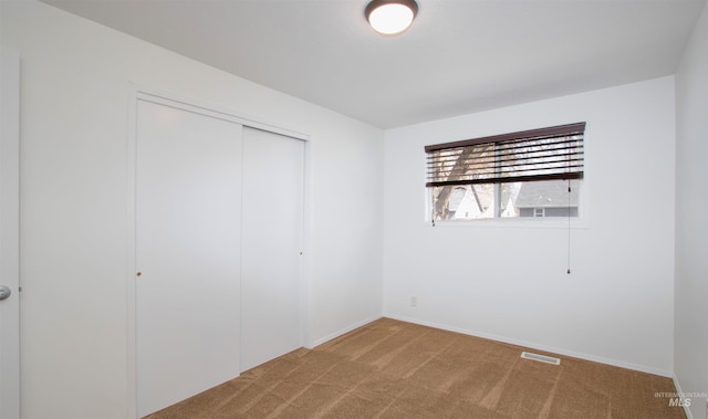 unfurnished bedroom featuring light carpet, visible vents, baseboards, and a closet