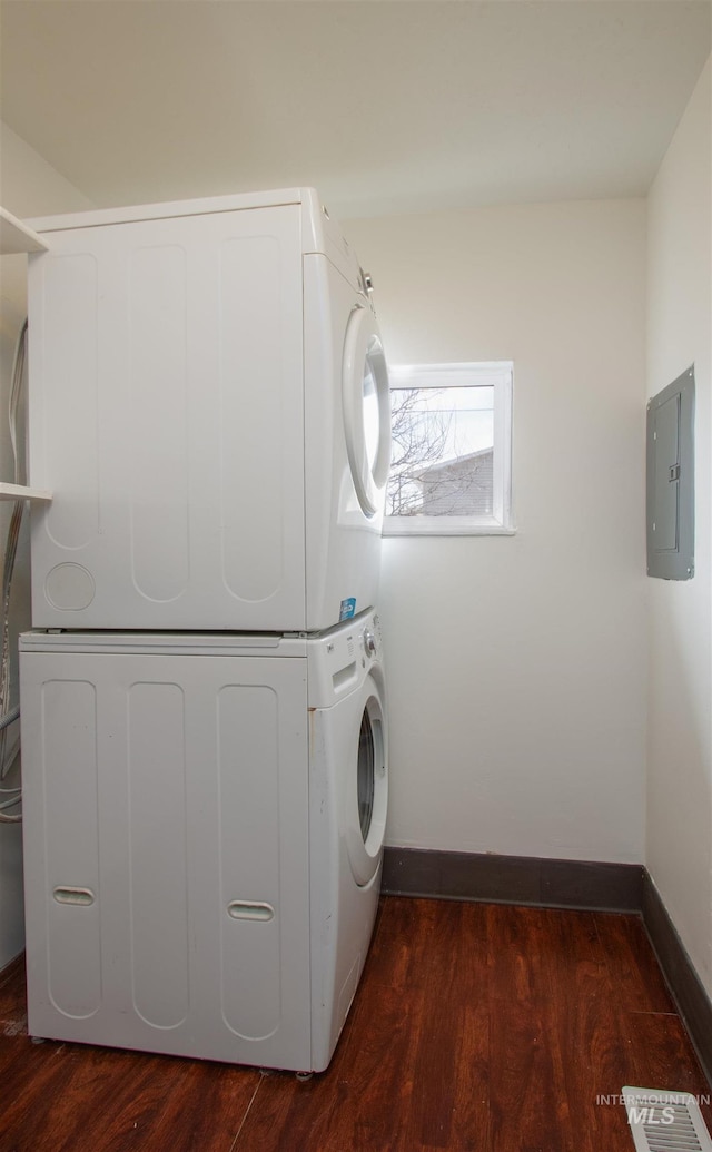 laundry area with visible vents, stacked washer and clothes dryer, electric panel, laundry area, and dark wood-style flooring