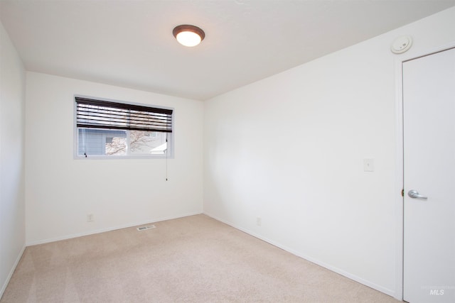 empty room featuring light colored carpet, visible vents, and baseboards