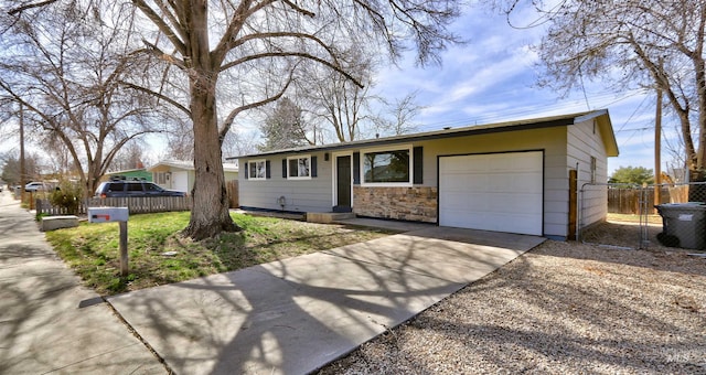 ranch-style house with stone siding, driveway, an attached garage, and fence