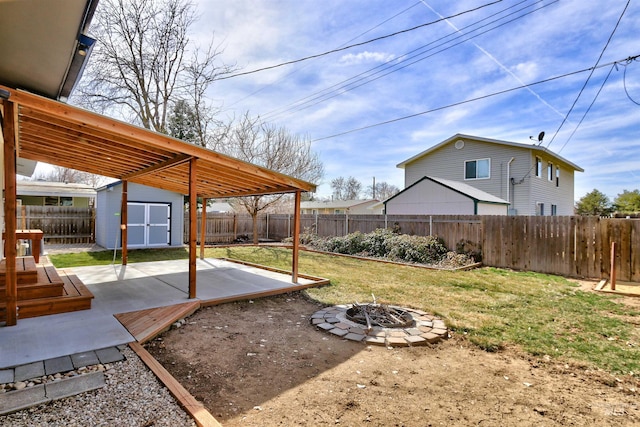 view of yard featuring a patio, a fenced backyard, a fire pit, a storage shed, and an outdoor structure